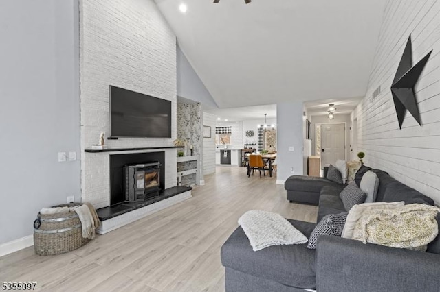 living room featuring baseboards, wood finished floors, ceiling fan with notable chandelier, and high vaulted ceiling