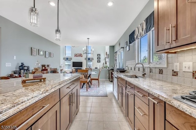 kitchen featuring light stone counters, a sink, open floor plan, and tasteful backsplash