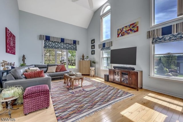 living room featuring baseboards, ceiling fan, high vaulted ceiling, and hardwood / wood-style flooring