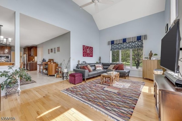 living area featuring a ceiling fan, high vaulted ceiling, and light wood-style flooring