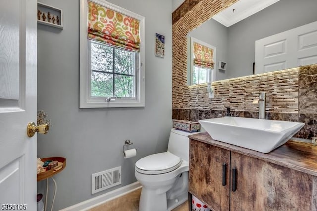 bathroom with visible vents, ornamental molding, vanity, toilet, and baseboards