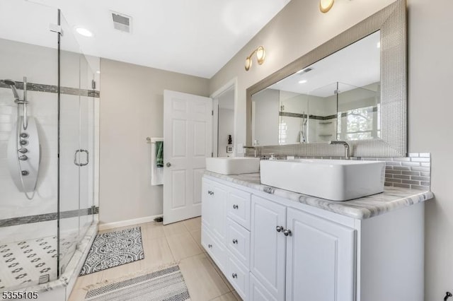 full bath with visible vents, a sink, a stall shower, and double vanity