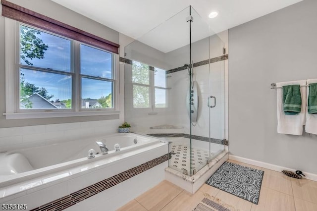 bathroom featuring baseboards, plenty of natural light, a stall shower, and a bath