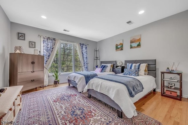 bedroom with baseboards, light wood finished floors, and visible vents