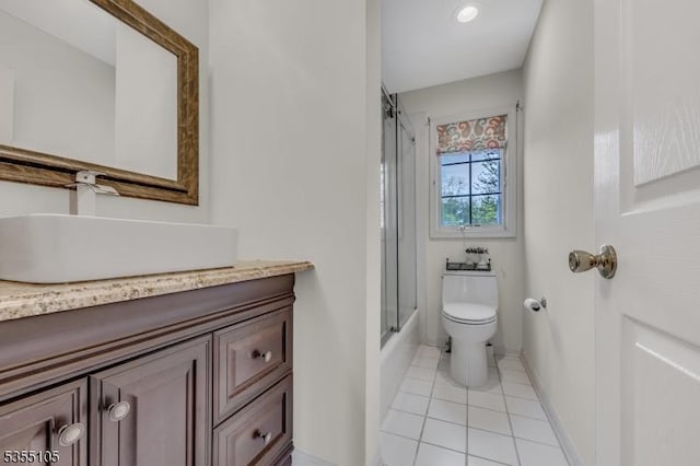 bathroom featuring tile patterned flooring, vanity, toilet, enclosed tub / shower combo, and baseboards
