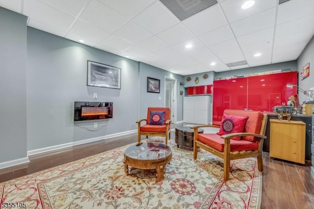interior space with baseboards, a paneled ceiling, and wood finished floors