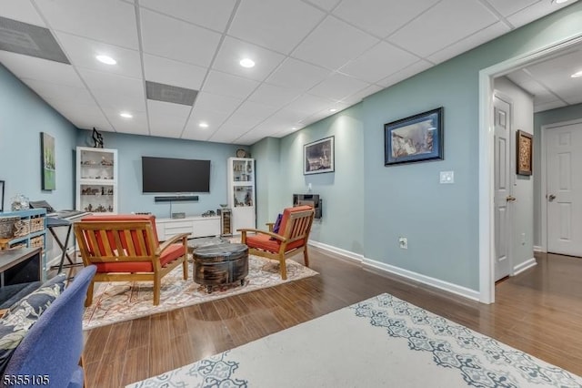 living room featuring baseboards, wood finished floors, and a paneled ceiling