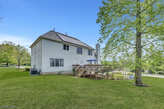 back of property featuring a lawn, a wooden deck, stairs, and a chimney