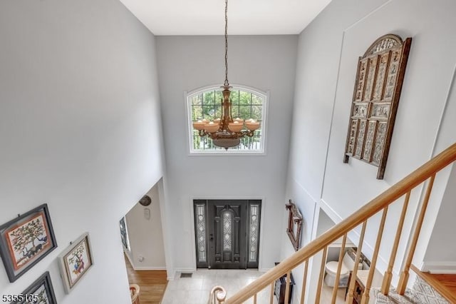 foyer featuring wood finished floors, stairs, a high ceiling, and a chandelier