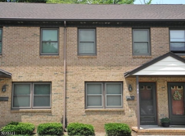 multi unit property with brick siding and a shingled roof