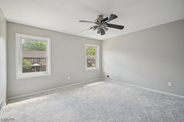 carpeted empty room featuring healthy amount of natural light, ceiling fan, and baseboards