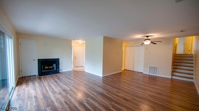 unfurnished living room featuring ceiling fan, visible vents, a fireplace, wood finished floors, and stairway