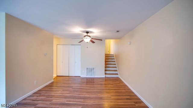 empty room with visible vents, a ceiling fan, wood finished floors, and stairway