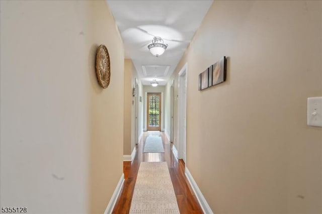 hallway with attic access, dark wood-type flooring, and baseboards