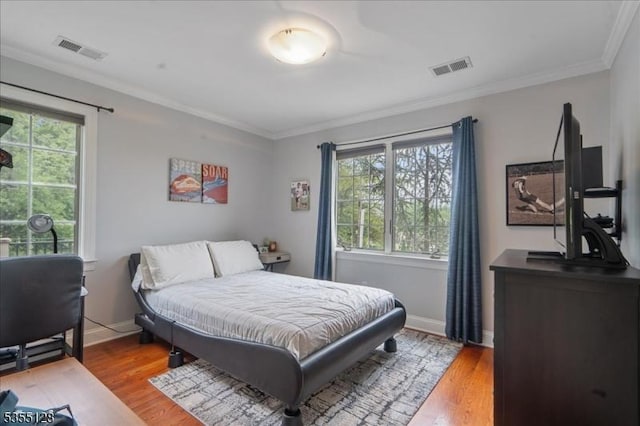bedroom with multiple windows, light wood-type flooring, crown molding, and baseboards