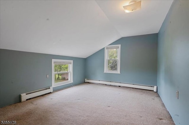 additional living space with baseboard heating, a baseboard radiator, carpet floors, vaulted ceiling, and healthy amount of natural light