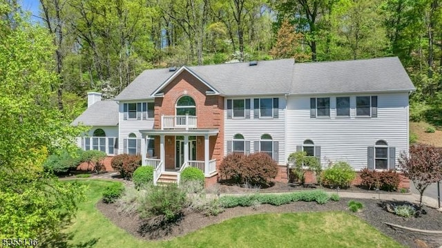 63 Twin Oaks Rd, Bridgewater Twp, NJ 08807 - view of front facade with a balcony, a chimney, brick siding, covered porch, and a front yard