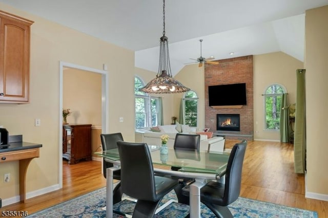 63 Twin Oaks Rd, Bridgewater Twp, NJ 08807 - dining area featuring light wood-type flooring, a fireplace, ceiling fan, vaulted ceiling, and baseboards