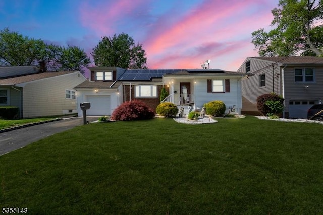 ranch-style house with a garage, driveway, a front yard, and solar panels