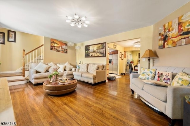 living room featuring stairs, a chandelier, and wood finished floors