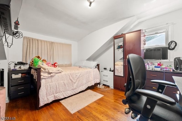 bedroom featuring wood finished floors, lofted ceiling, and cooling unit