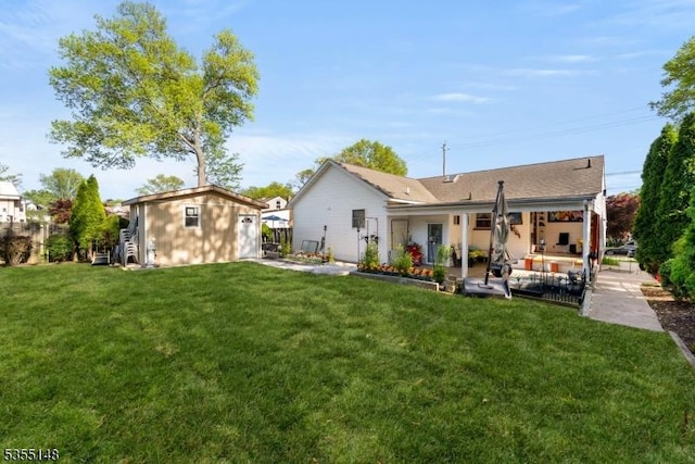back of house with an outbuilding, a patio, and a yard