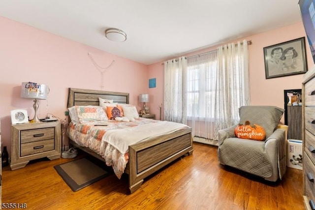 bedroom with wood finished floors and a baseboard radiator