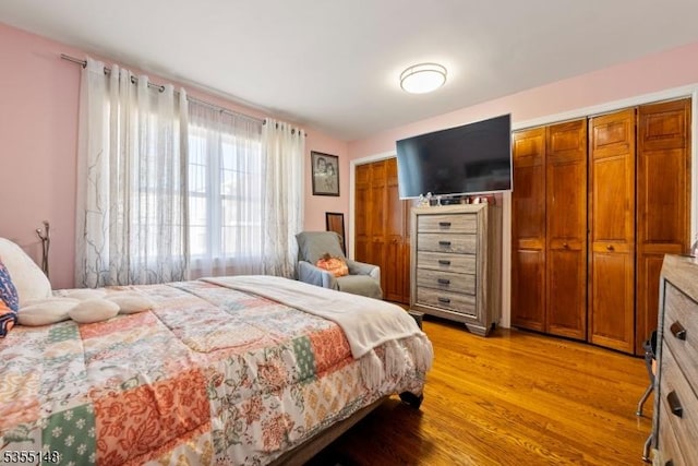bedroom featuring light wood-style flooring and multiple closets