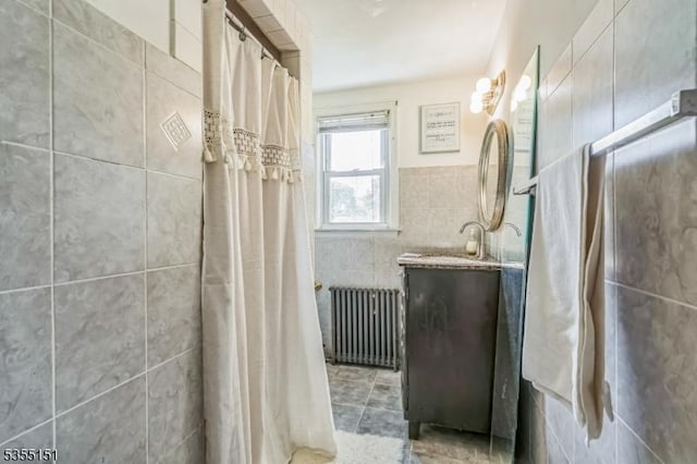 full bath featuring a shower with curtain, tile walls, radiator, and vanity