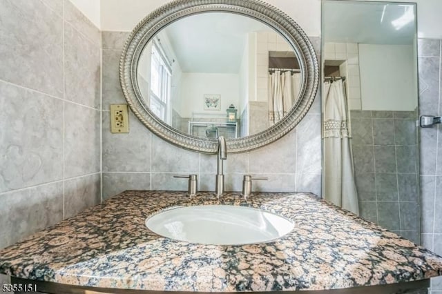 bathroom with vanity, curtained shower, and tile walls