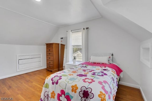 bedroom with baseboards, vaulted ceiling, and wood finished floors