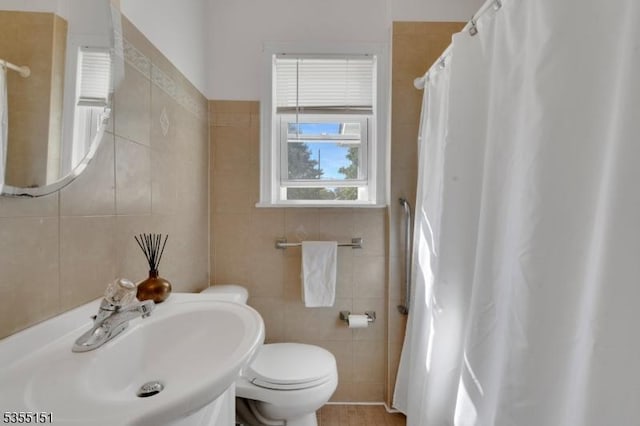 full bath featuring a sink, curtained shower, toilet, and tile walls