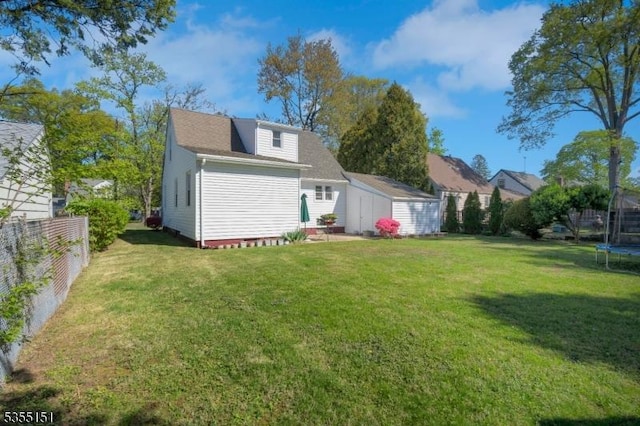 back of property with a storage unit, a trampoline, an outdoor structure, and a yard