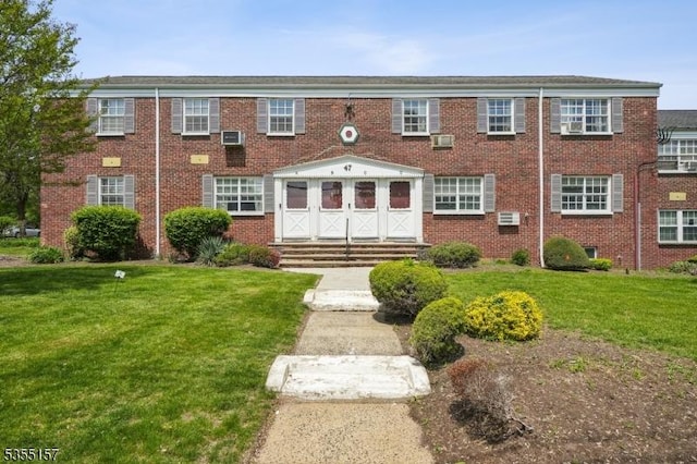 multi unit property with brick siding and a front yard