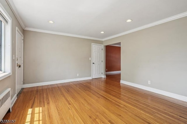 empty room featuring baseboards, ornamental molding, radiator heating unit, and light wood finished floors