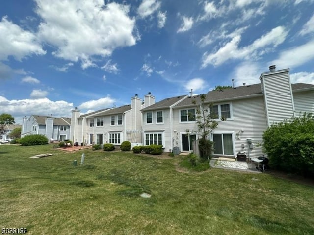 rear view of property featuring a lawn, a residential view, and a chimney