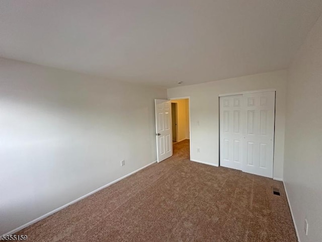 unfurnished bedroom featuring carpet flooring, baseboards, visible vents, and a closet