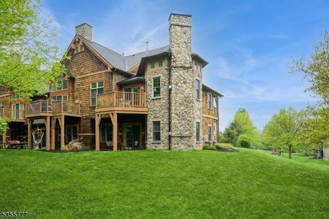 rear view of house featuring a yard, a chimney, and stone siding