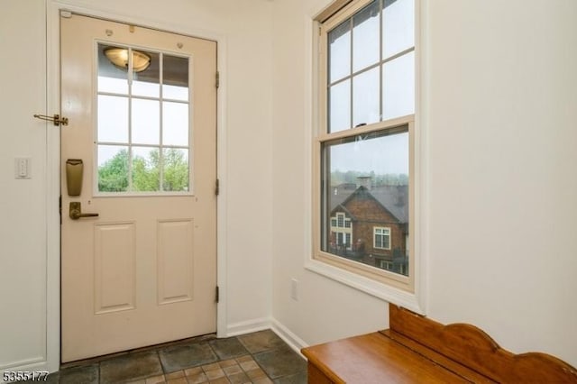 doorway with baseboards and stone finish floor