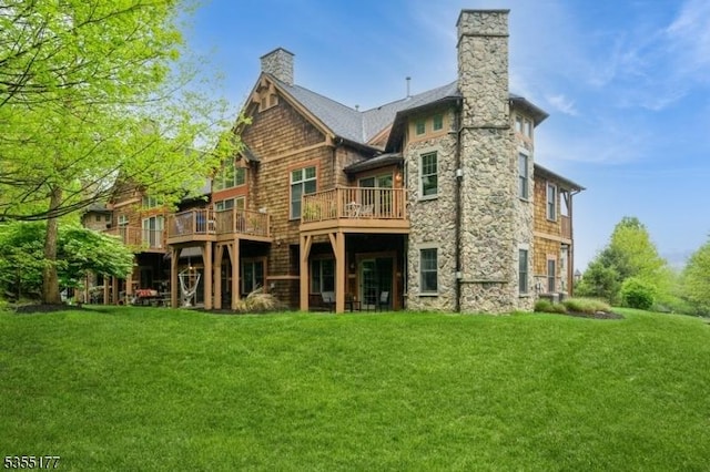 back of house featuring a yard, a chimney, a wooden deck, and stone siding