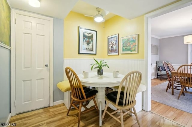 dining area with wood finished floors, wainscoting, and ceiling fan