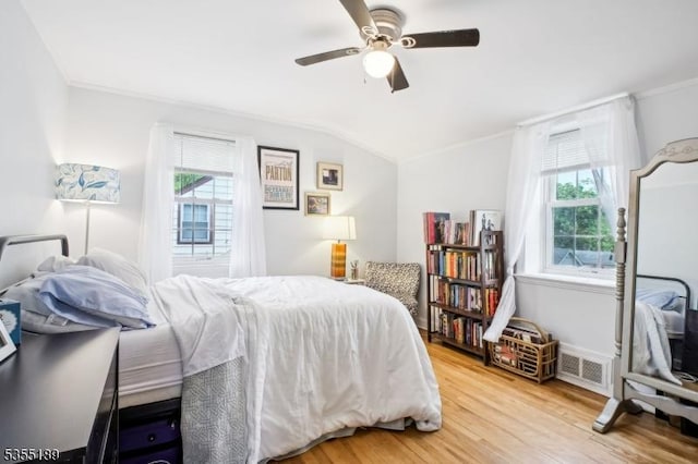 bedroom with lofted ceiling, ornamental molding, wood finished floors, and a ceiling fan