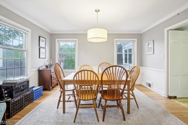 dining area featuring light wood-type flooring, healthy amount of natural light, and ornamental molding