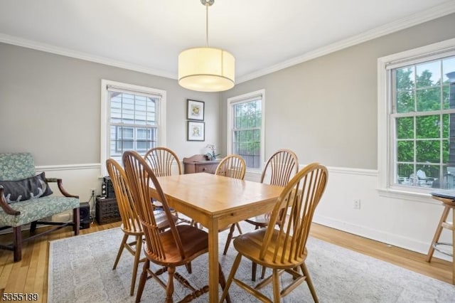 dining space featuring light wood-style flooring and crown molding