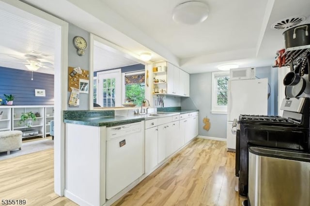 kitchen with white appliances, light wood-style flooring, a sink, white cabinetry, and baseboards