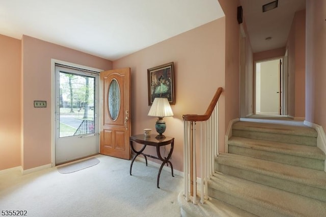 carpeted foyer featuring baseboards, stairs, and visible vents