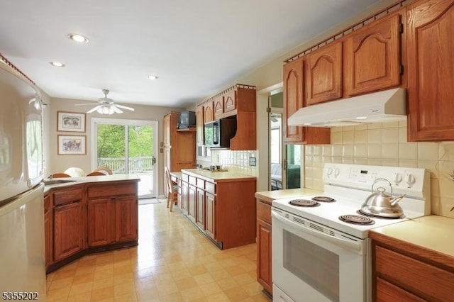 kitchen featuring ceiling fan, brown cabinetry, under cabinet range hood, and white appliances