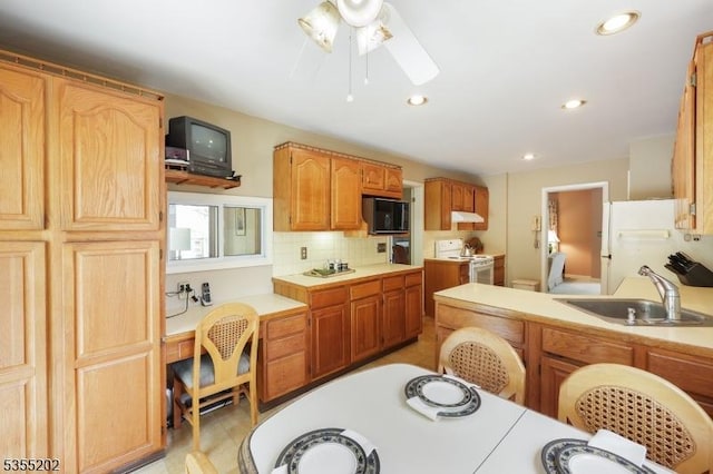 kitchen featuring a sink, white appliances, light countertops, a ceiling fan, and under cabinet range hood