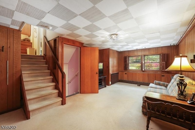 interior space featuring wood walls, light carpet, and stairway