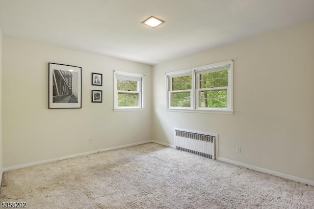 unfurnished room featuring radiator, baseboards, and carpet